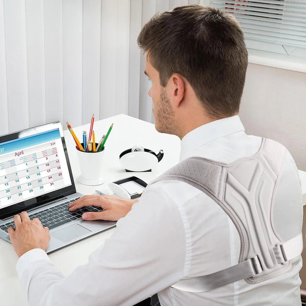Man using a laptop with a posture corrector in an office setting